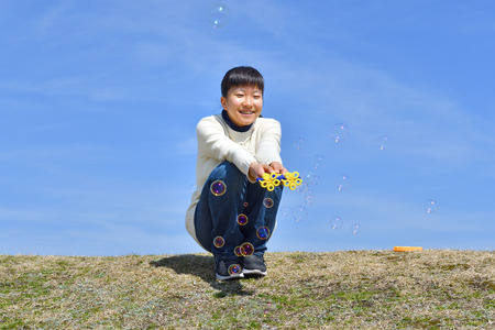 Japanese girl playing with soap bubbles in the blue sky