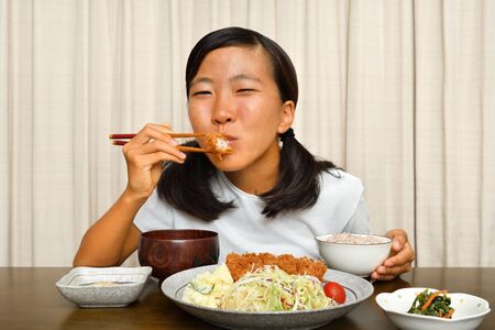 Japanese girl enjoys having dinnerの写真素材