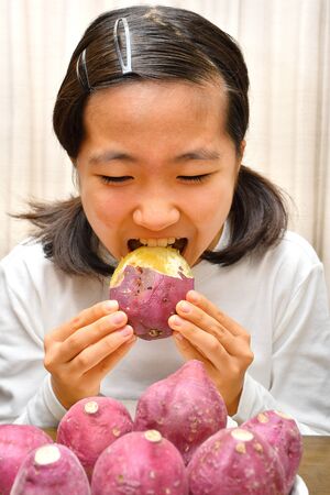 Japanese girl enjoys having sweet potatoesの写真素材