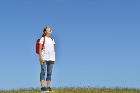 Japanese Elementary School Girl Looking up in the Blue Skyの写真素材