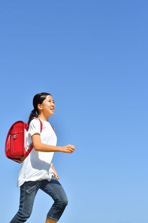 Japanese Elementary School Girl running in the Blue Skyの写真素材