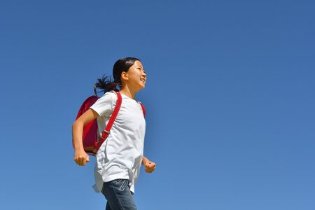 Japanese Elementary School Girl running in the Blue Skyの写真素材