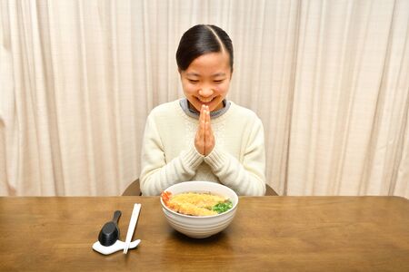 Japanese girl enjoys having buckwheat noodle with deep fried shrimpの写真素材