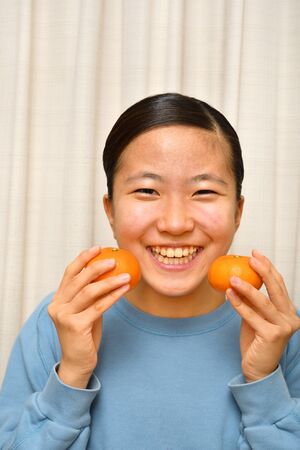 Japanese girl enjoys having mandarin orangeの写真素材