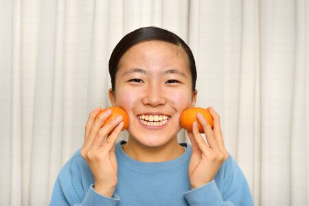 Japanese girl enjoys having mandarin orangeの写真素材