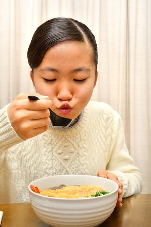 Japanese girl enjoys having buckwheat noodle with deep fried shrimpの写真素材