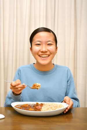 Japanese girl enjoys having curry and riceの写真素材