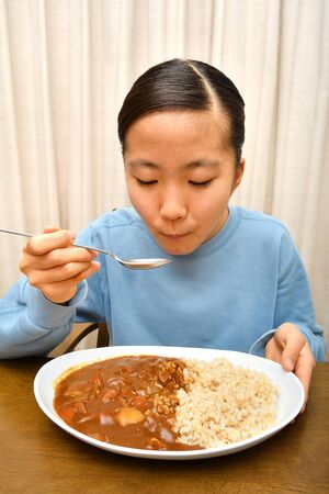 Japanese girl enjoys having curry and riceの写真素材