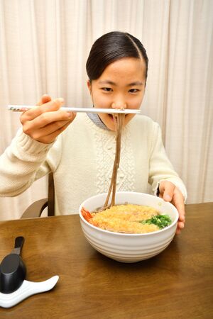 Japanese girl enjoys having buckwheat noodle with deep fried shrimpの写真素材