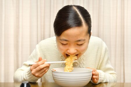 Japanese girl enjoys having buckwheat noodle with deep fried shrimpの写真素材