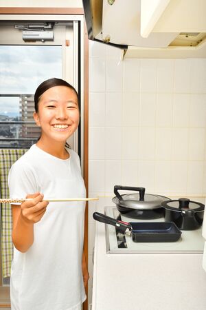 Japanese girl enjoys cooking in the kitchenの写真素材