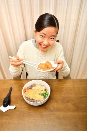 Japanese girl enjoys having buckwheat noodle with deep fried shrimpの写真素材