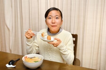 Japanese girl enjoys having buckwheat noodle with deep fried shrimpの写真素材