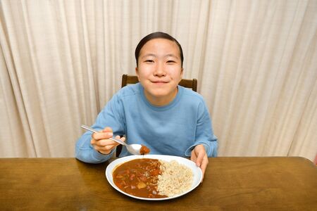 Japanese girl enjoys having curry and riceの写真素材