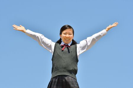 Japanese girl raising hands in the blue skyの写真素材