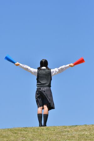 Japanese girl cheering in the blue sky rear viewの写真素材
