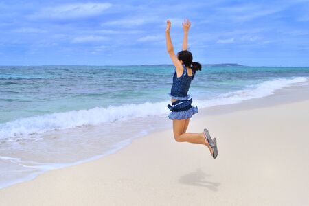 Japanese girl jumping in the beach - Rear view Okinawa Miyakojimaの写真素材