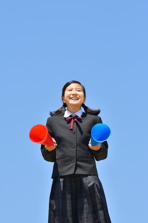 Japanese girl cheering in the blue sky with megaphonesの写真素材