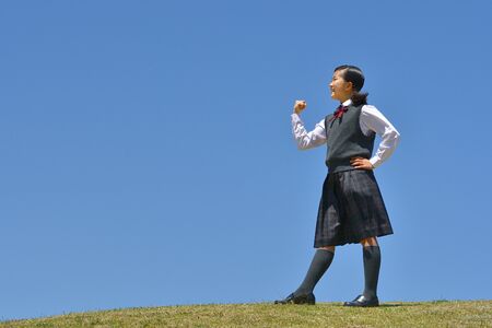Japanese girl striking a victory pose in the blue skyの写真素材