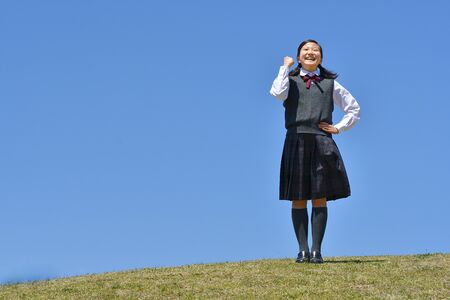 Japanese girl striking a victory pose in the blue skyの写真素材