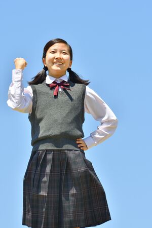 Japanese girl strikes a victory pose in the blue skyの写真素材