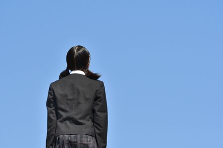 Japanese girl standing in the blue sky rear viewの写真素材