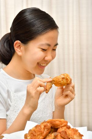 Japanese girl enjoys having fried chickenの写真素材