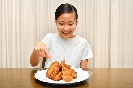 Japanese girl enjoys having fried chickenの写真素材