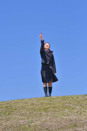 Japanese girl pointing in the blue skyの写真素材