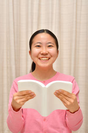 Japanese girl reading book in the living roomの写真素材