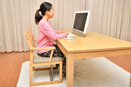 Japanese girl operating personal computer in the living roomの写真素材