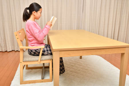 Japanese girl reading book in the living roomの写真素材