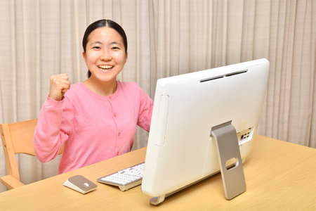 Japanese girl operating personal computer in the living roomの写真素材