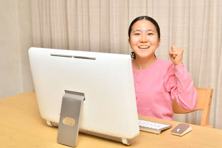 Japanese girl operating personal computer in the living roomの写真素材