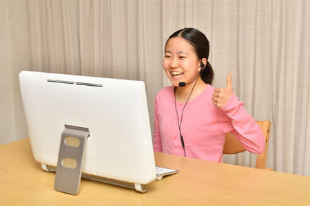 Japanese girl operating personal computer in the living roomの写真素材
