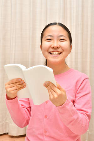 Japanese girl reading book in the living roomの写真素材