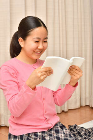 Japanese girl reading book in the living roomの写真素材