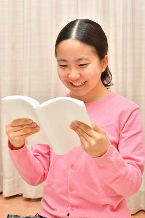 Japanese girl reading book in the living roomの写真素材