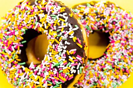 Color spray chocolate donuts on a yellow backgroundの写真素材