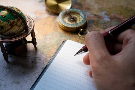 Small globe and business notebook on world map background
