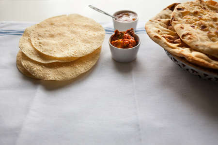 Handmade Indian flat breads served with mango chutney and pickle on the white tableclothの写真素材