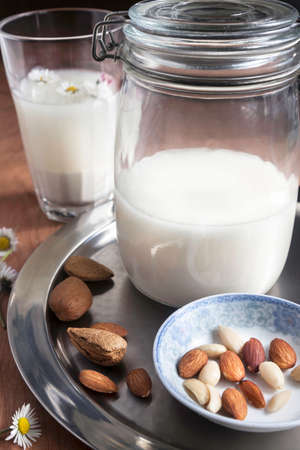 Glass and jar of homemade almond milk with raw almonds