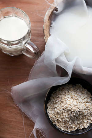 Bowl and glass of homemade oat milk with raw oatssの写真素材