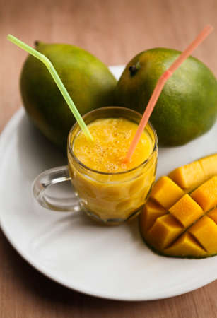 Fresh mango smoothie with ripe mangoes on the white plateの写真素材
