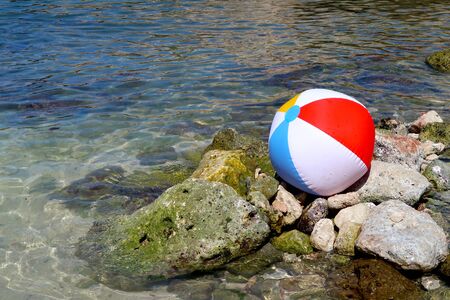 Inflatable beach ball on the rock beach in Italy with sea in the background - summer holiday vacations concept - Italy, Monopoli, Adriatic Seaの写真素材
