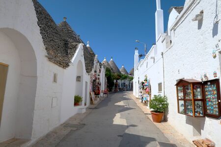 The traditional Trulli houses in the street of Alberobello city, Italy, Apulia region, Adriatic Sea with typical souvenir shopsの写真素材