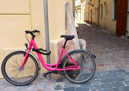 Pink bicycle leaning against the wall in the street of Prague city, Czech Republic, a typical street of the old town in the background. It is locked to the lamppost.の写真素材
