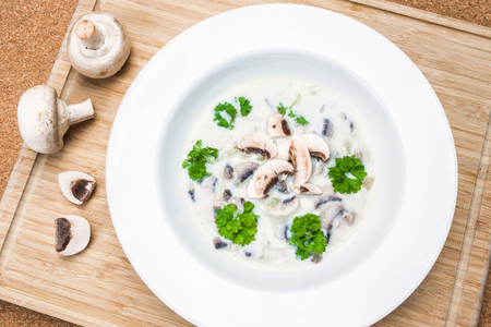 Top View Mushroom Soup with Raw Champignons on Breadboardの写真素材