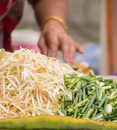Hand of street vender preparing bean sprouts and scallion for Pad Thaiの写真素材