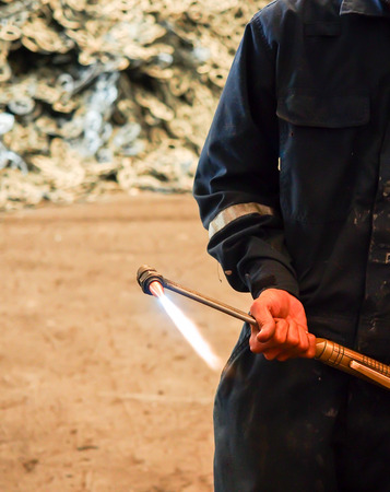 Worker with Oxygen Acetylene metal cutting torch in recycle factory